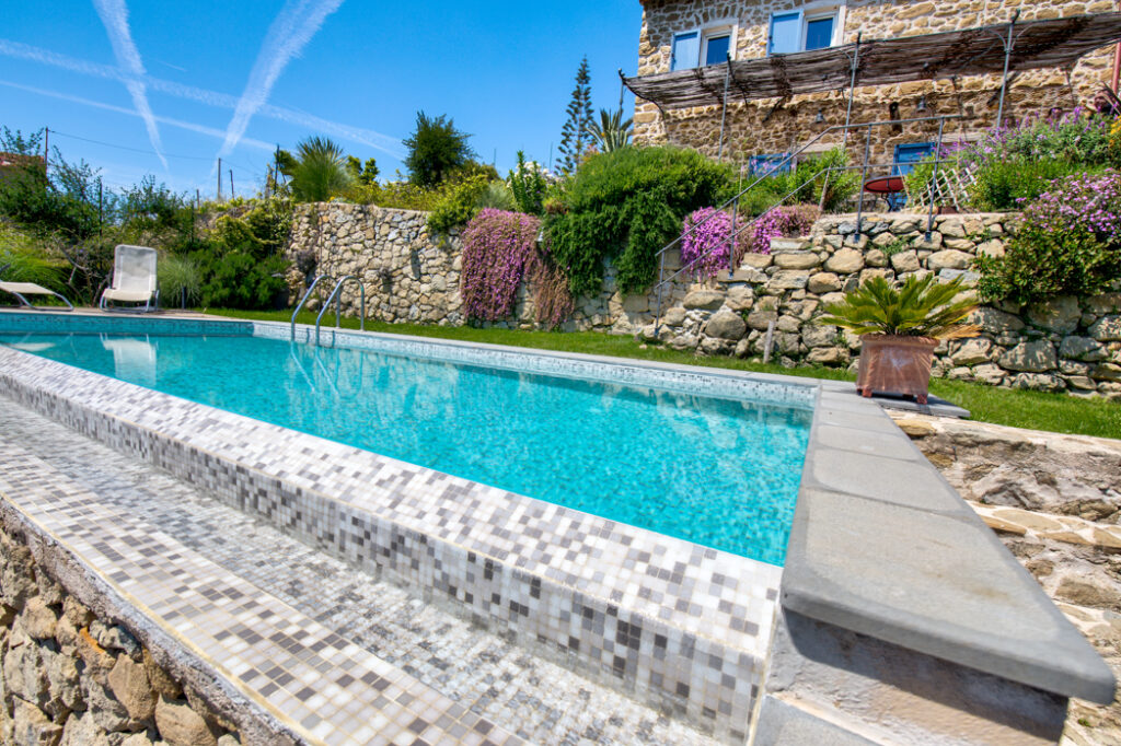 Piscina di design con acqua cristallina, bordo elegante e finiture di alta qualità, immersa in un ambiente raffinato per un relax totale.