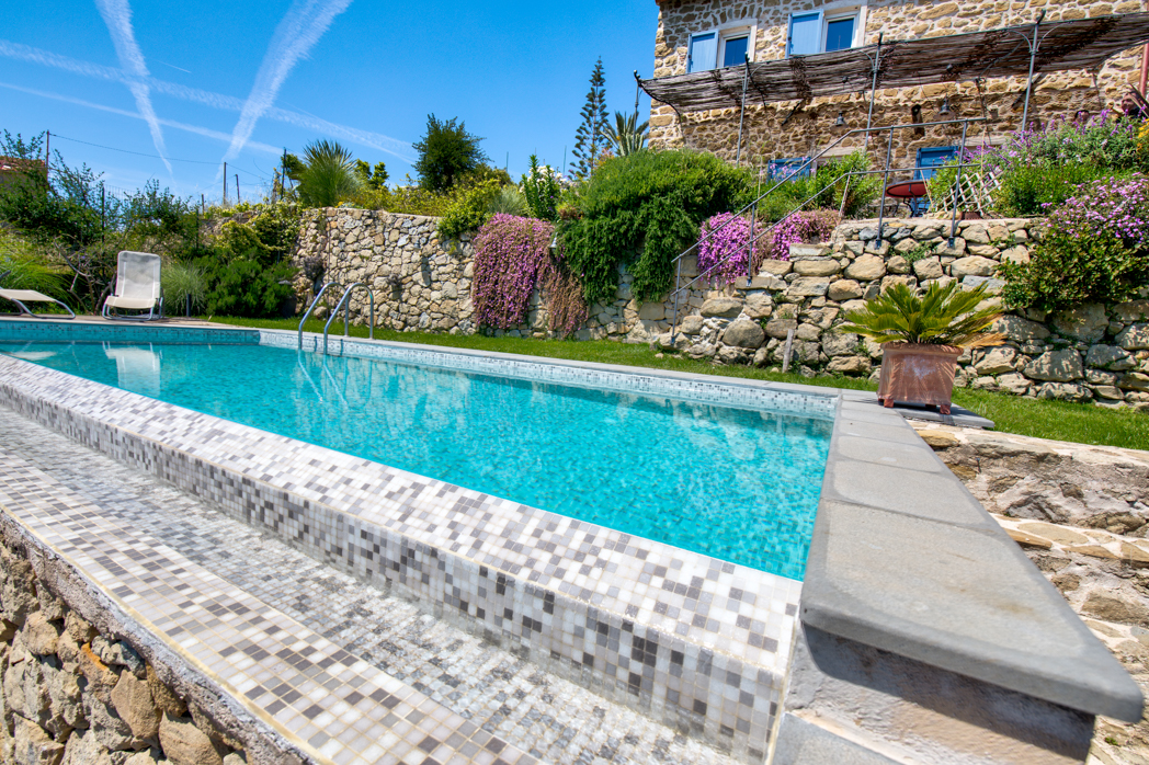 Piscina di design con acqua cristallina, bordo elegante e finiture di alta qualità, immersa in un ambiente raffinato per un relax totale.